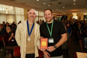 NCBC President Joe Burns presents this month's book prize to James Hopkin of Jensten Insurance Brokers